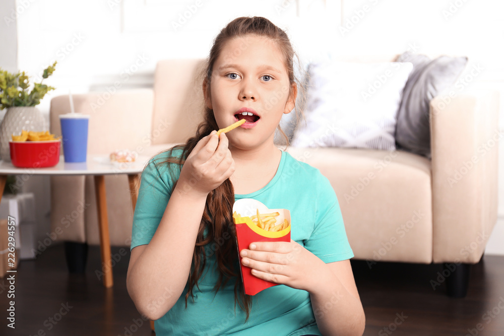 Overweight girl eating french fries indoors Overweight girl eating french fries indoors