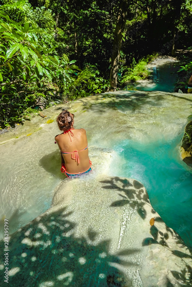 Fototapeta premium Tourist sitting on the rock on the water in erawan waterfall national park kanchanaburi thailand