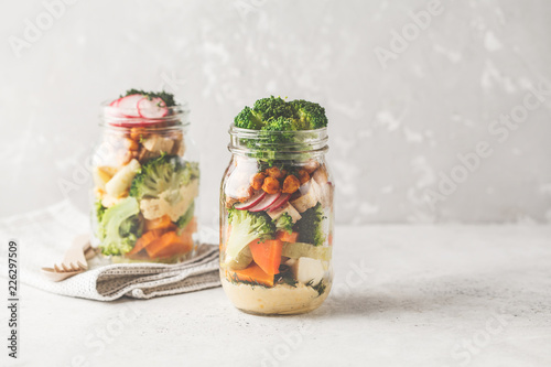 Healthy Homemade Mason Jar Salad with baked vegetables, hummus, tofu and chickpeas, copy space.