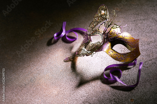 Decorative gold carnival mask with purple ribbons