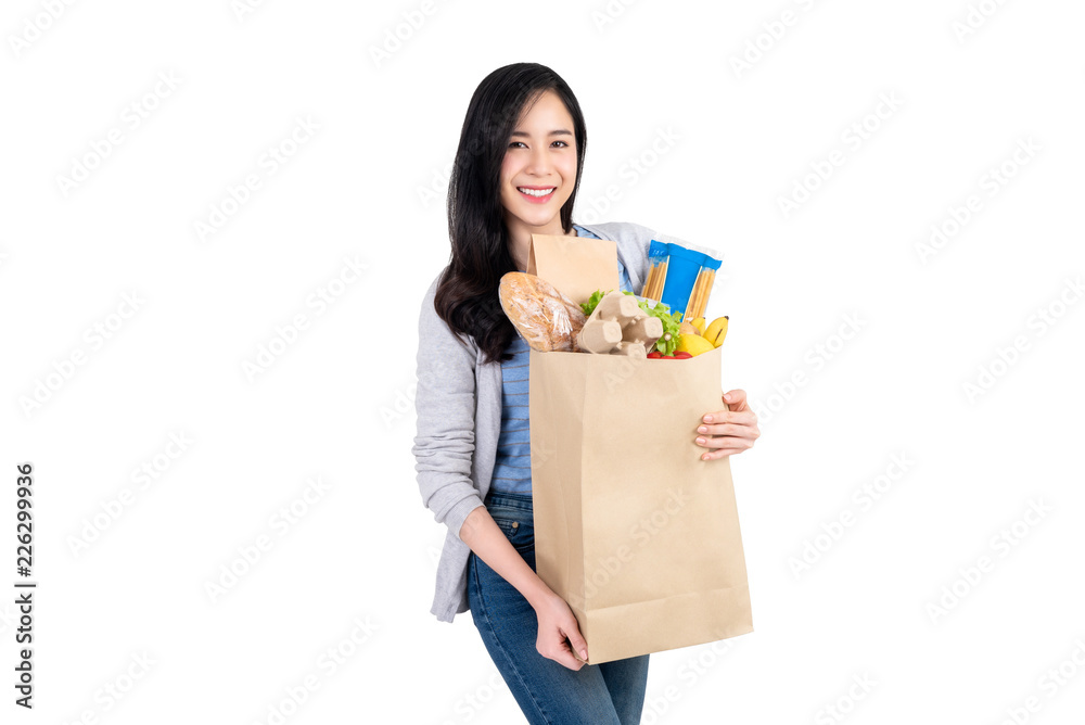 Smiling Asian woman holding paper shopping bag full of vegetables and groceries Smiling Asian woman holding paper shopping bag full of vegetables and groceries