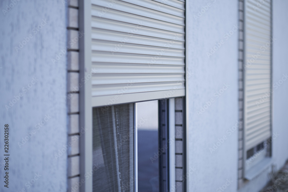 Fototapeta premium Window with half-closed roller shutter, closeup