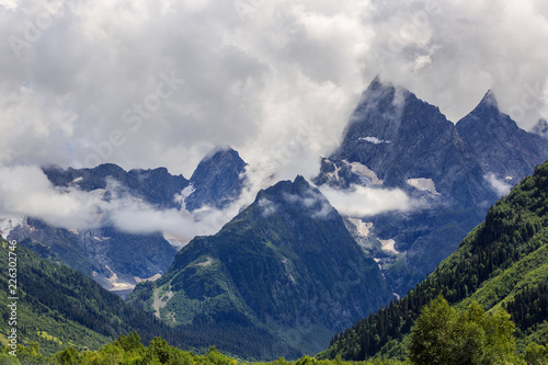 Peak of the mountain with glaciers against the background of clouds and sky. Caucasian ridge, Russia.