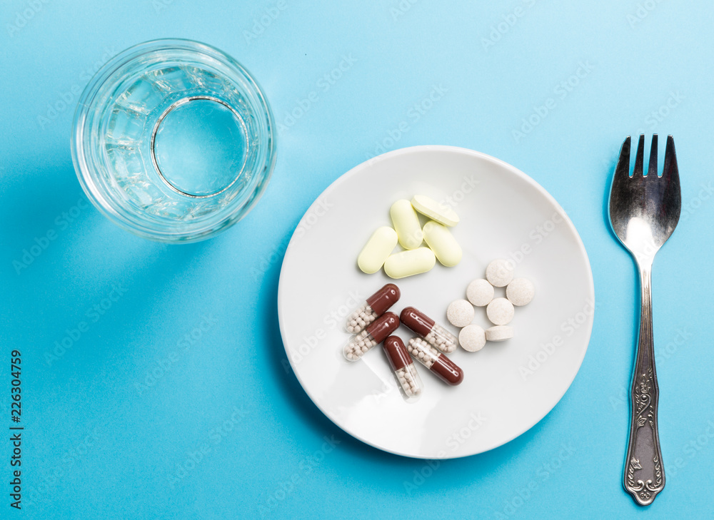 A fork with a pile of medicines and a glass of water. A fork with a pile of medicines and a glass of water.
