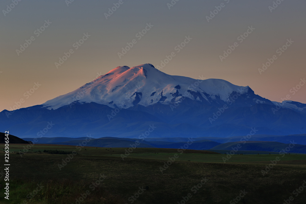 Mount Elbrus at dawn. View of the sunlit slopes of the volcano from the northwest. The North Caucasus in Russia.