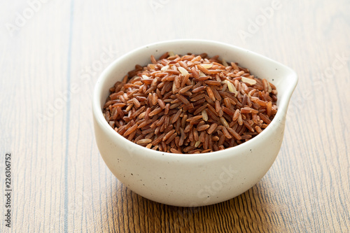 brown rice for healthy white bowl on wood background