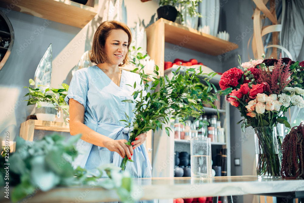 Female florist holds fresh flowers in floral shop