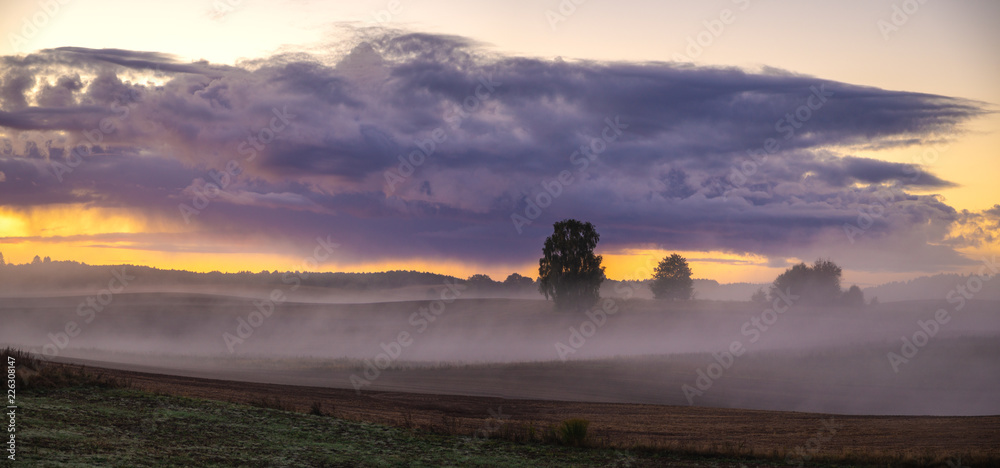 Fototapeta premium beautiful, dramatic sky over an autumn field enveloped in the morning mists-Poland, Drawskie Lakeland