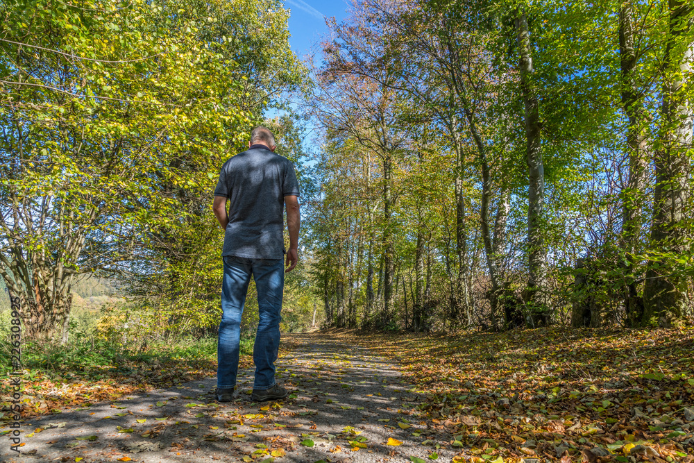 Einsamer Mann auf einem Feldweg im Herbst