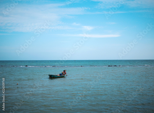 one small fishing boat on the blue sea and clear sky © Nikkikii