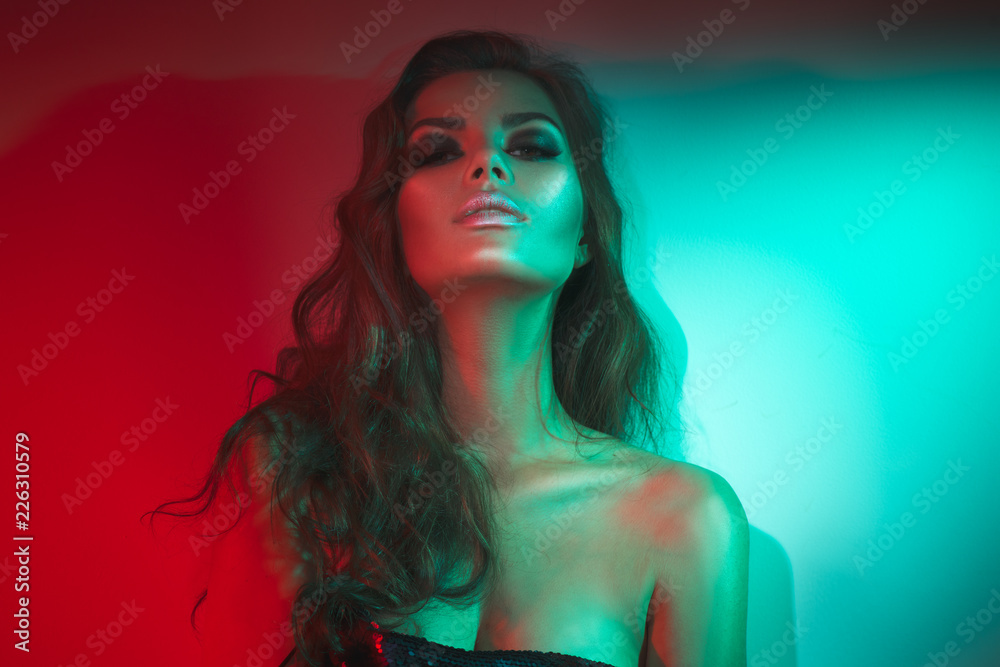 Fashion model brunette woman in colorful bright neon lights posing in studio. Beautiful sexy girl, trendy glowing makeup, metallic silver lips Fashion model brunette woman in colorful bright neon lights posing in studio. Beautiful sexy girl, trendy glowing makeup, metallic silver lips