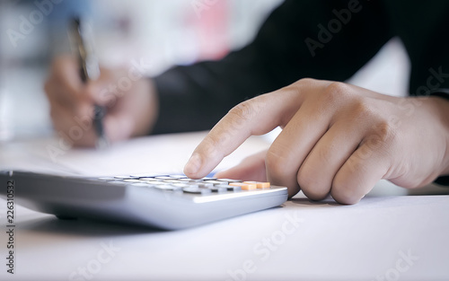 Close up businessman hand using calculator.