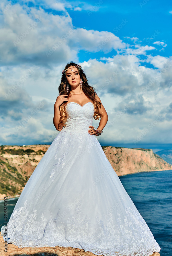 Brunette bride in a long white dress near the sea