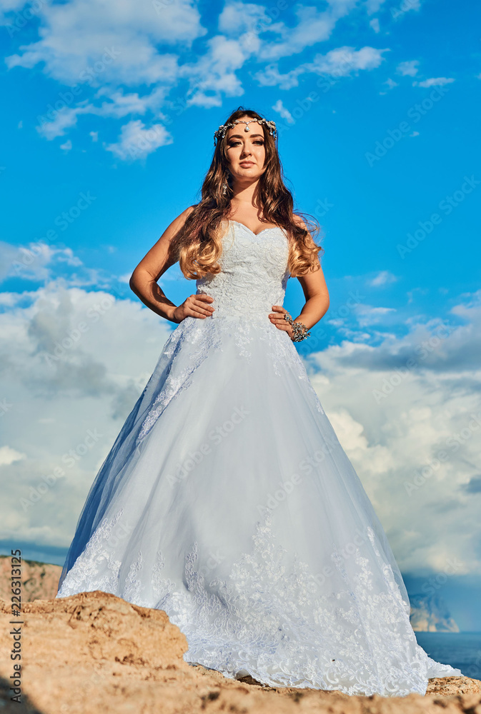 Brunette bride in a long white dress near the sea Brunette bride in a long white dress near the sea