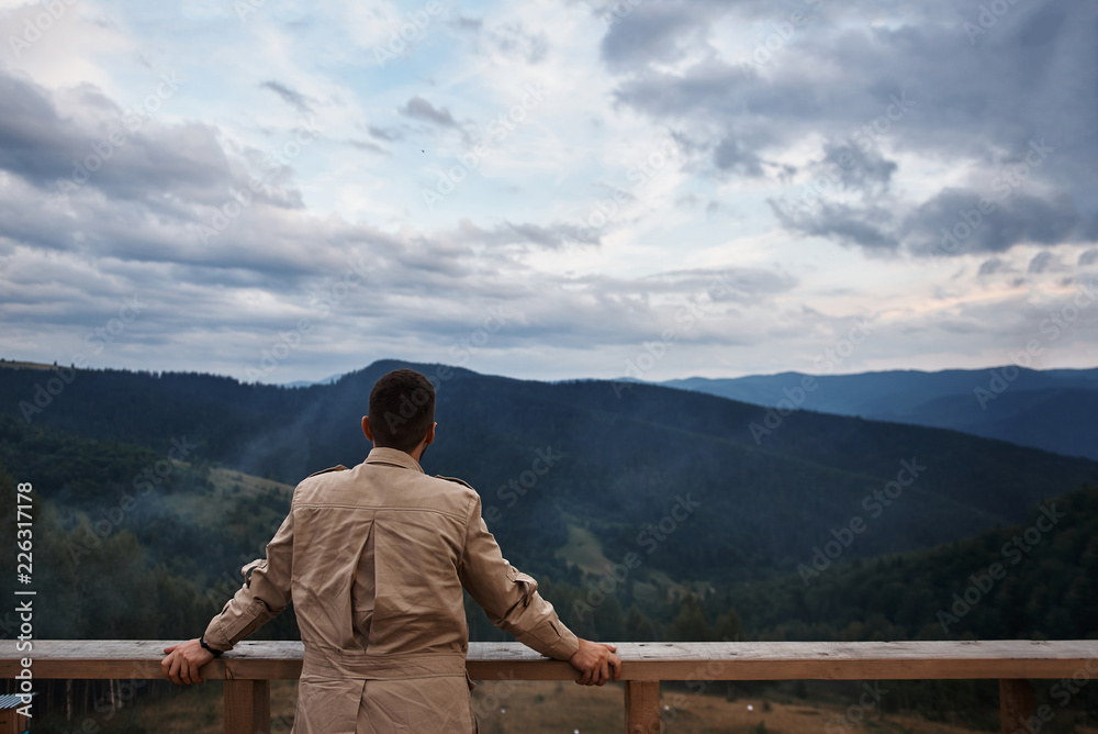 Panoramic shot of Carpathian mountains covered with coniferous forest and a pleasant man enjoying this view
