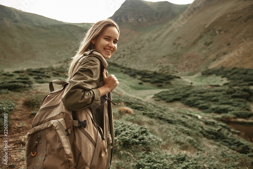 Confident hiker. Positive experienced traveler feeling happy in the mountains and smiling while carrying backpack