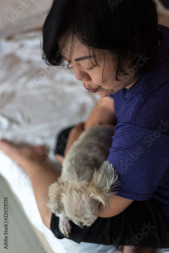 Asian woman hugging dog so cute on bed in bedroom