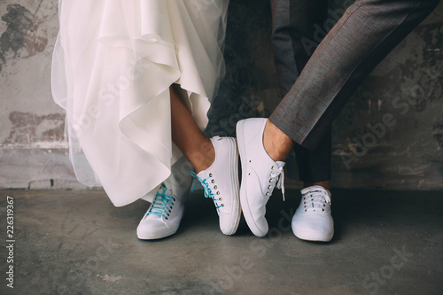 Hipster couple standing together wearing white sneakers. Wedding in sneakers, love. Soft focus tehnic, wedding style clothes