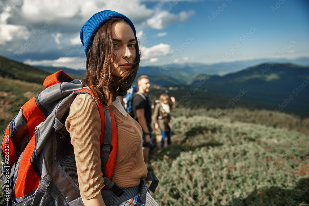 Serious traveler. Peaceful thoughtful young traveler carrying heavy backpack and looking at you while being in the mountains