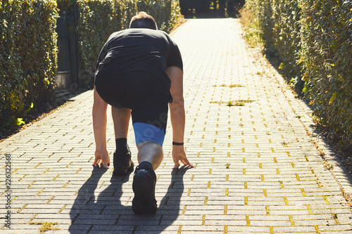 Athlete man in running crouch start pose in sunlight during sunset
