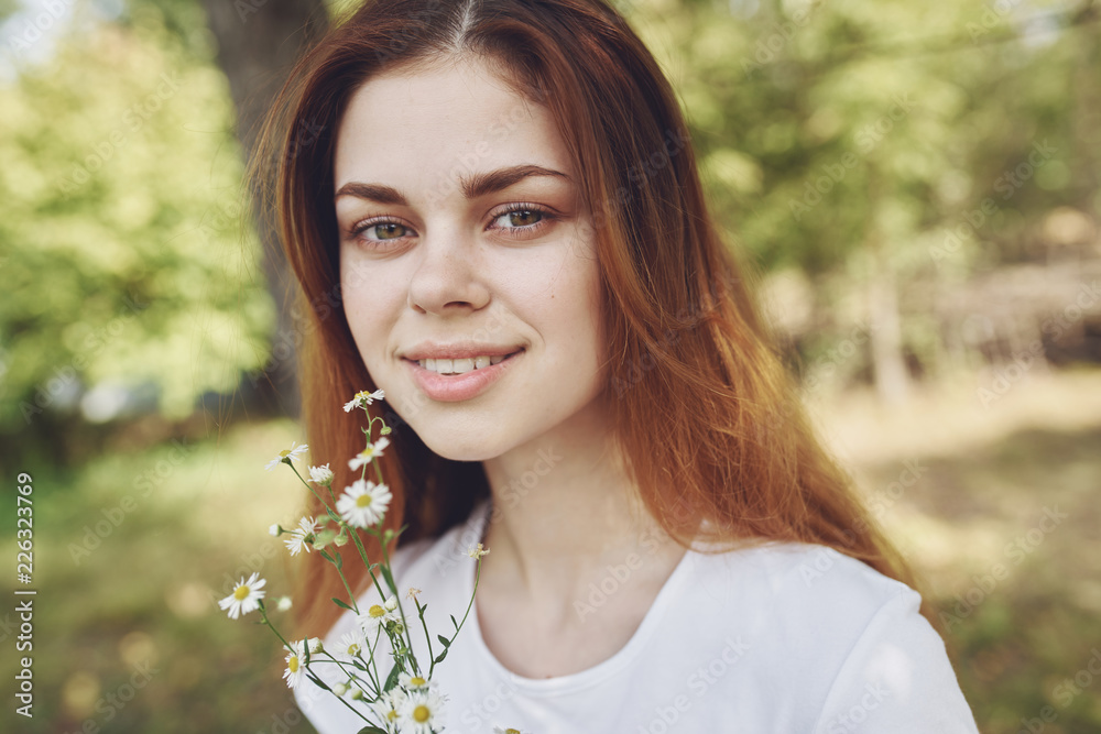 red-haired woman in nature holds flowers in her hand red-haired woman in nature holds flowers in her hand
