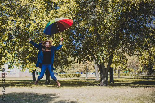 Attractive young casual girl walking in the park with umbrella, autumn day. Weather and people concept - nice lady with umbrella on nature. England rain   photo