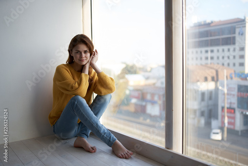 beautiful woman in a sweater and jeans sitting on the windowsill Free Download beautiful woman in a sweater and jeans sitting on the windowsill - GFXLoad