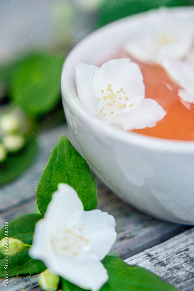 Spa and wellness setting with sea salt, oil essence, jasmin flowers and towels on wooden background. Relax and treatment therapy.