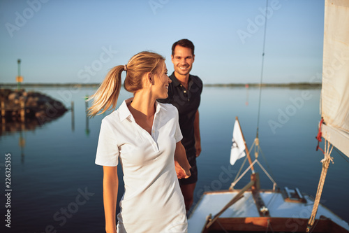 Smiling young couple walking along the deck of their yacht