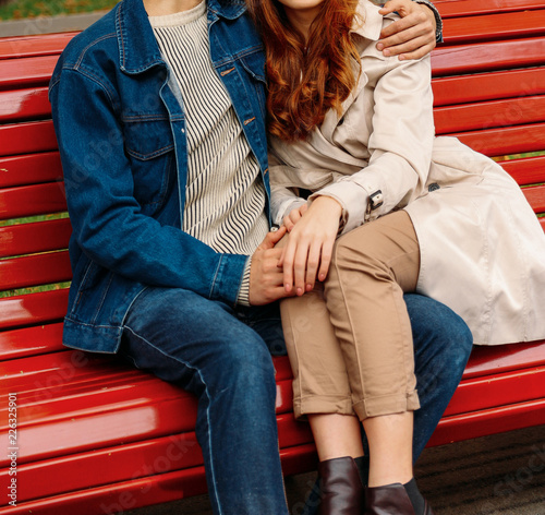 couple sitting on a bench, legs of a girl on a guy, a man huggin © Skripnik Olga