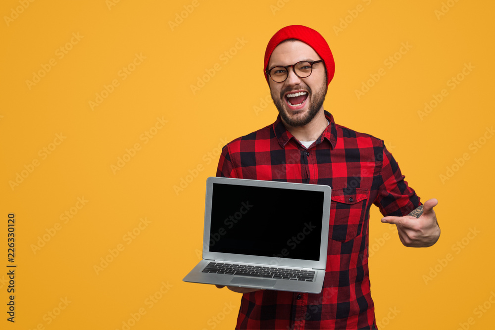 Excited hipster pointing at new laptop Excited hipster pointing at new laptop