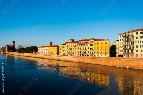Beautiful morning on the river in Pisa, with small houses and blue sky © Vladyslav