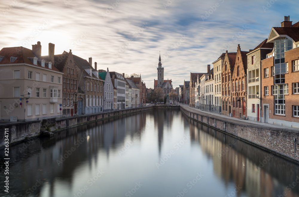 Canals of Bruges in a sunny winter afternoon with the church of our lady in the background, Bruges, Belgium