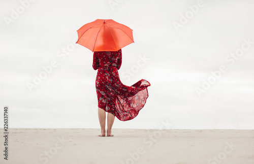 Woman under umbrella standing at the seaside