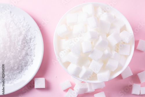 Sugar in cubes abd crystaline, flat lay on pink background