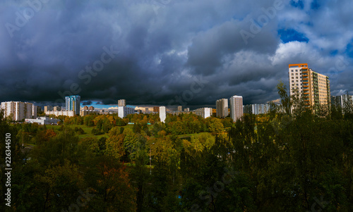 Panorama residential disctrict of Moscow at autumn with dark beautiful rainy clouds in the blue sky, soviet buildings, a large park – panoramic view of the city in high resolution
