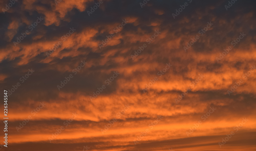 Dramatic sunset sky with orange colored clouds.
