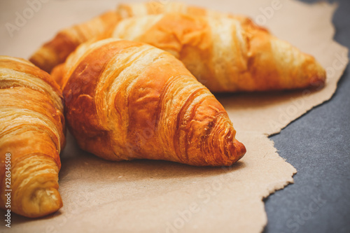 Four croissants on brown craft paper on a dark contrasting background. photo