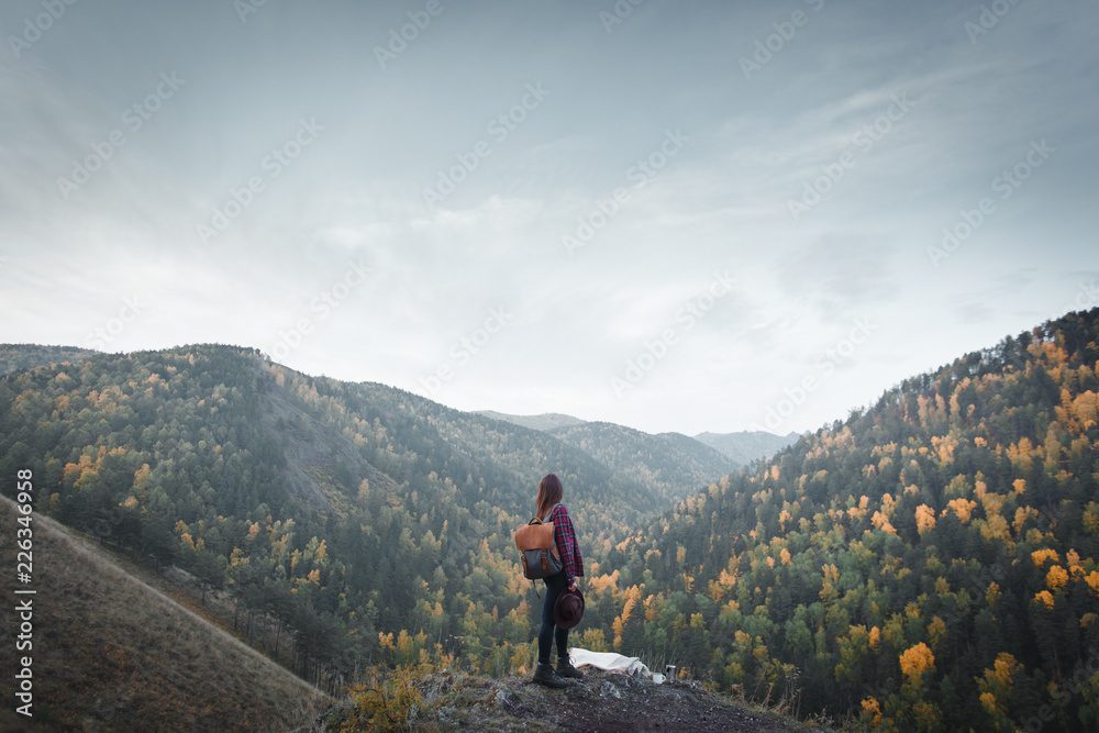 Young girl with backpack and hat in trekking boots on the background of autumn nature Young girl with backpack and hat in trekking boots on the background of autumn nature