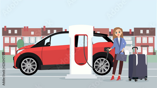 Woman traveler with baggage charges an electric car at a charging station 