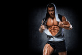 Young handsome athlete bodybuilder, in beautiful sportswear, demonstrates abdominals, against a dark background. Concept - power, beauty, biceps, triceps, sports equipment, gym, sports nutrition.