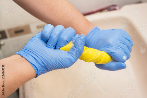 Man cleaning bathroom, draining a sponge cloth