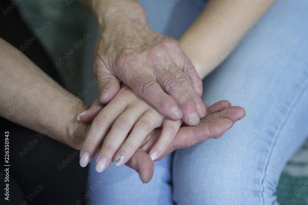 Fototapeta premium Hands of an elderly woman holding the hand of a younger woman.