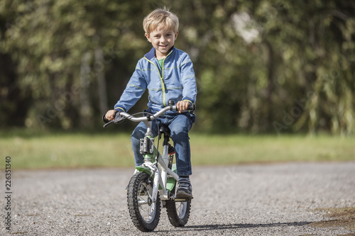 Fototapeta Naklejka Na Ścianę i Meble -  Smiling little boy on a bicycle while learning to ride