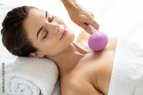 Woman is enjoying Asian massage therapy with herbal compress photo