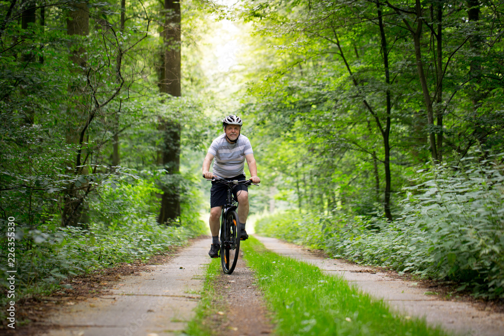 Senior man biking in forest, enjoying healthy active lifestyle outdoors in summer Senior man biking in forest, enjoying healthy active lifestyle outdoors in summer