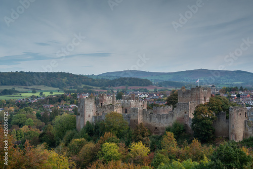 View across autumnal woodland to Ludlow Castle built by the Normans with the Clee Hills in the background.