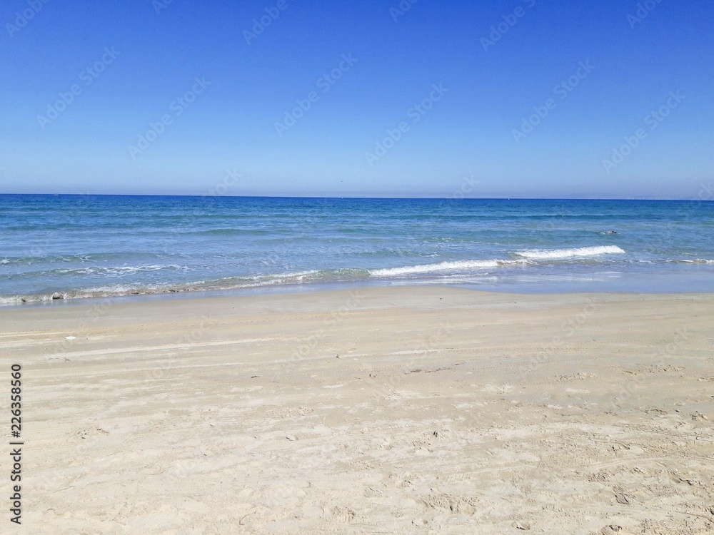 Empty sand beach with blue sea and blue sky background.