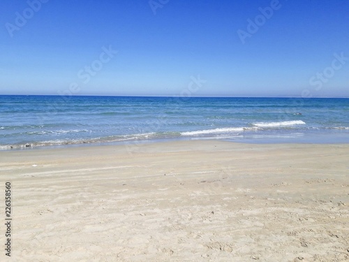 Empty sand beach with blue sea and blue sky background.
