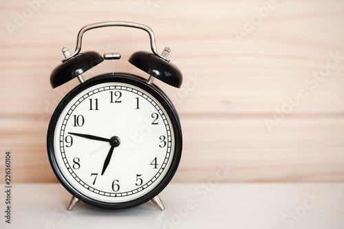 Vintage alarm clock is on white bedside table